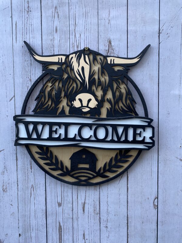 Welcome sign with a highland coo