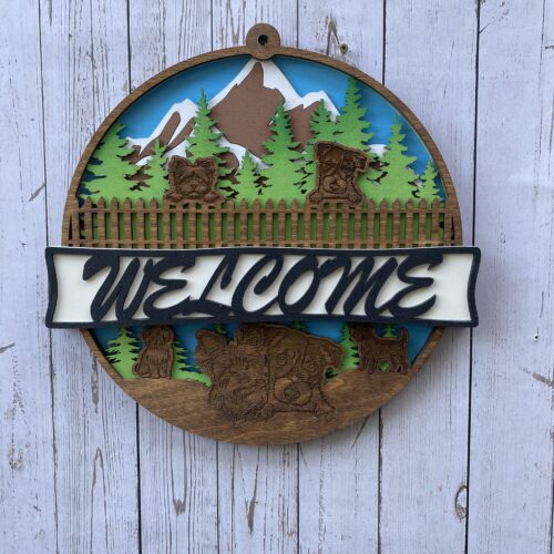 Welcome sign with mountains and trees